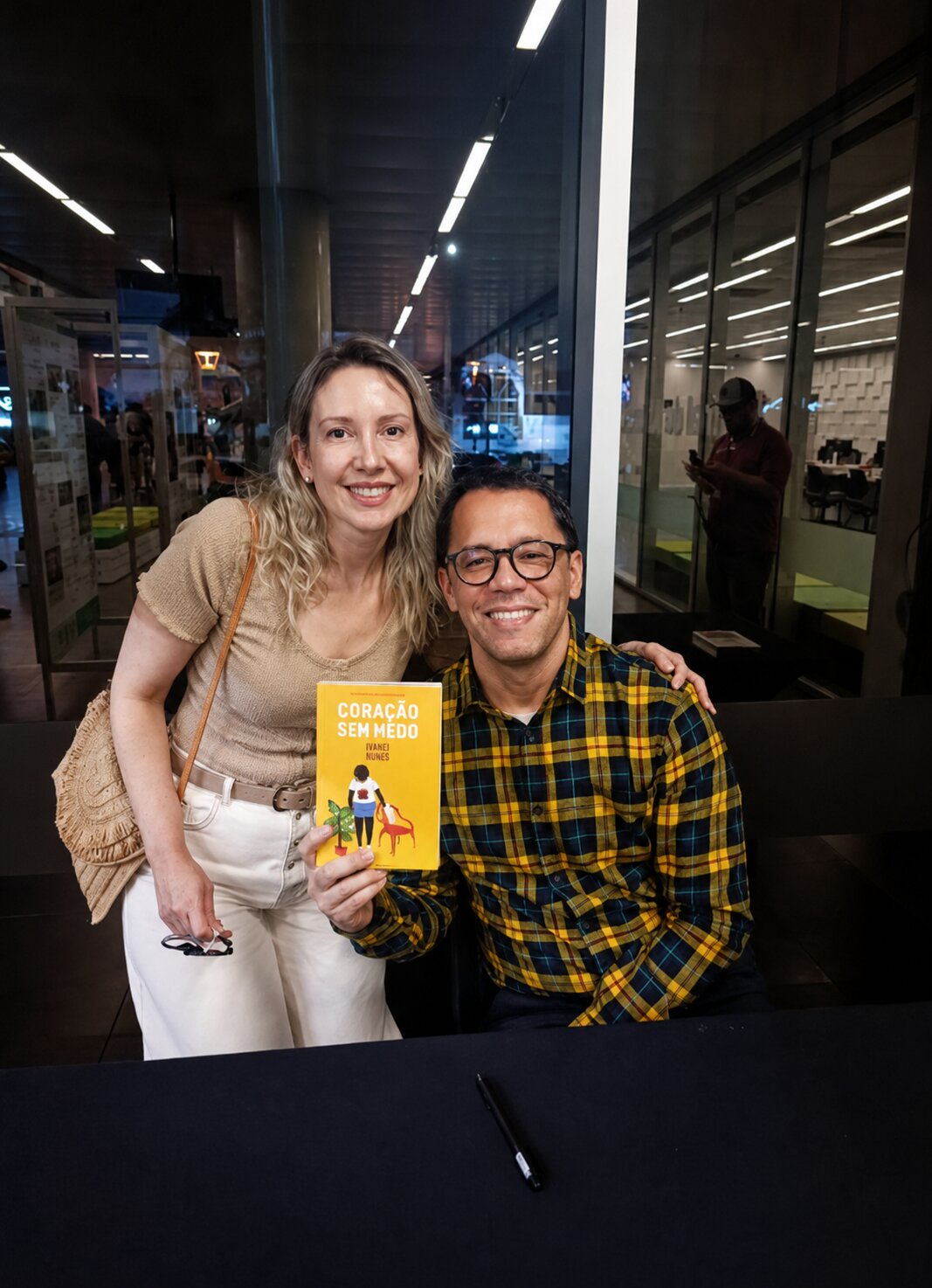 Karina Vezzaro ao lado do escritor Itamar Vieira Júnior, segurando o livro Coração sem Medo